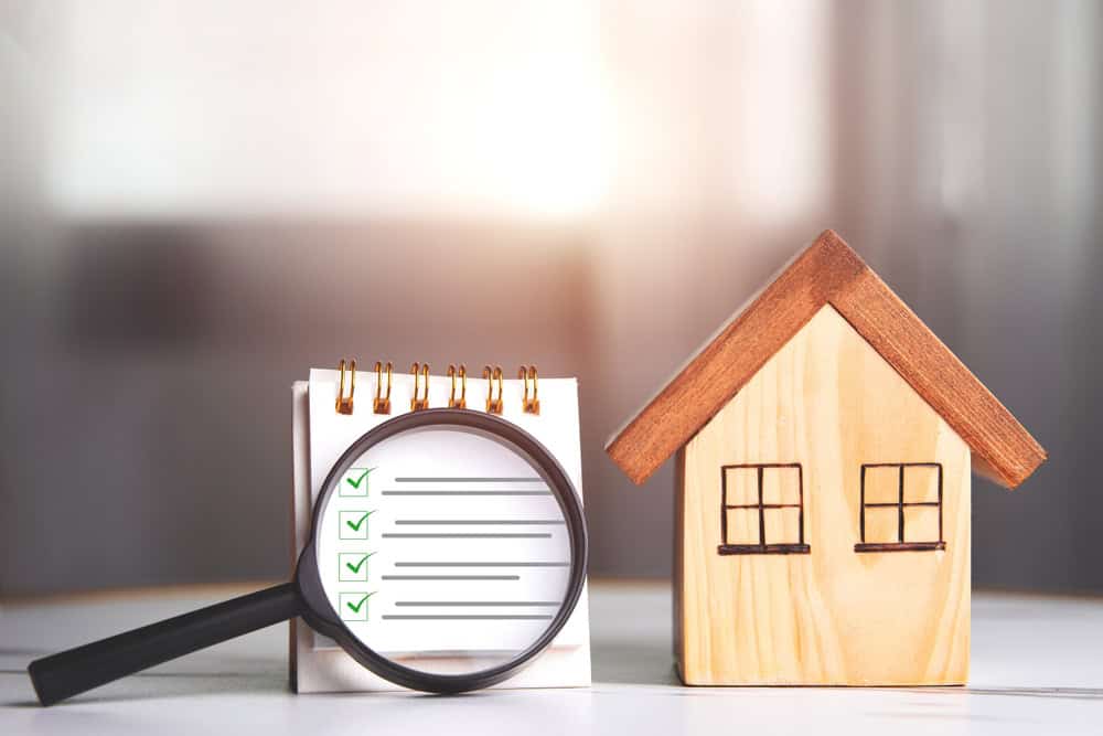 Home inspection. Wooden house and magnifying glass with a checklist for home with copy space